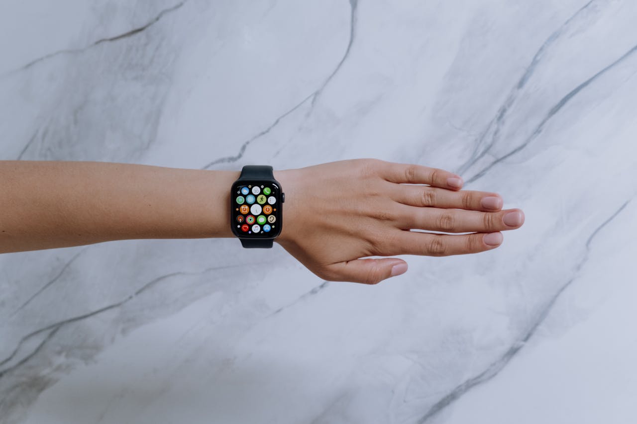 contact-img Overhead view of a smartwatch on an arm against a marble background representing modern technology.