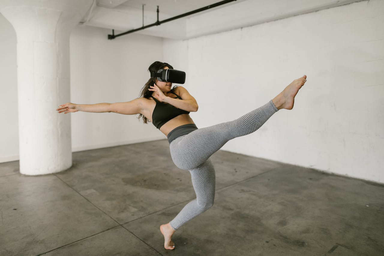 A woman practicing dance moves with a virtual reality headset in a minimalist indoor studio setting.