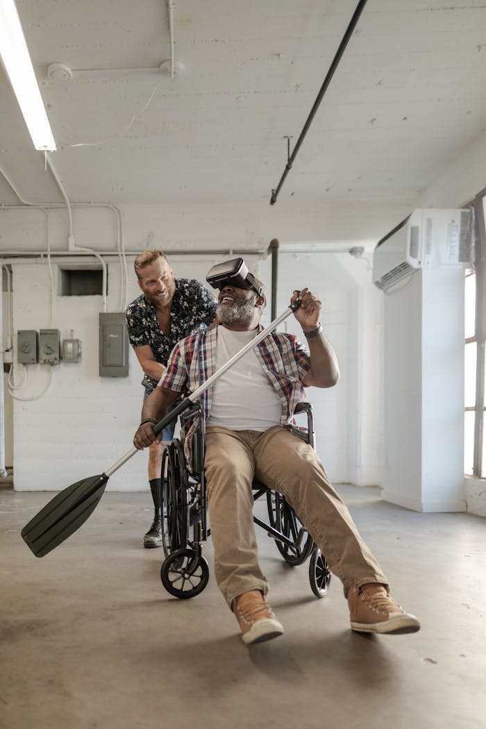 gallery-6 Man in wheelchair using VR headset for rehabilitation, assisted by friend.